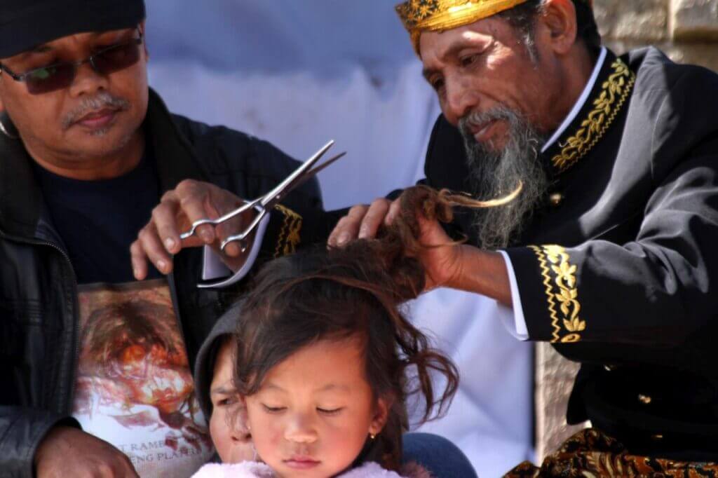 Salah seorang anak berambut gimbal dipotong rambutnya di depan Candi Puntadewa dalam Festival budaya Dieng atau Dieng Culture Festival (DCF) 2012 di Kompleks Candi Arjuna, Dataran Tinggi Dieng, Jawa Tengah, Minggu, 1 Juli 2012. [TEMPO/STR/Aris Andrianto; AAN2012070108]