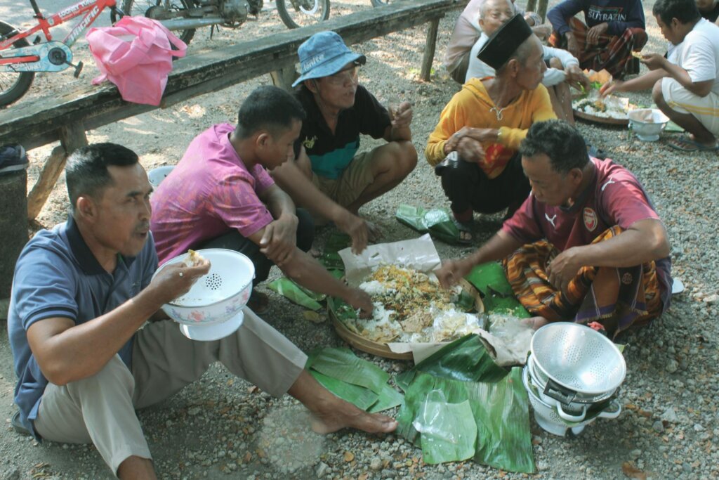 Penduduk Desa Sugihmanik tengah menikmati ambengan yang telah disediakan sebagai rangkaian dalam prosesi pembersihan Telaga Sendangsari